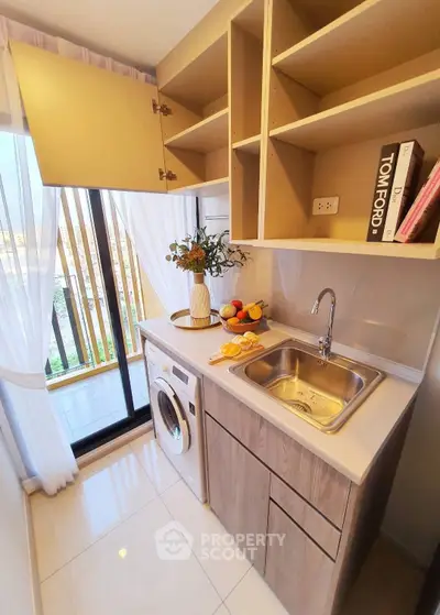 Modern kitchen with washing machine and open shelving, featuring a bright balcony view.