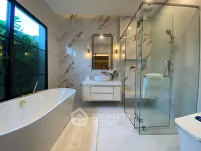 Luxurious modern bathroom with elegant marble walls and spacious glass shower enclosure.