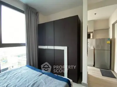 Modern bedroom with large wardrobe and view of kitchen area, featuring sleek design and natural light.