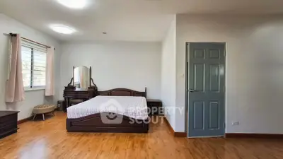 Spacious bedroom with wooden flooring and elegant furniture