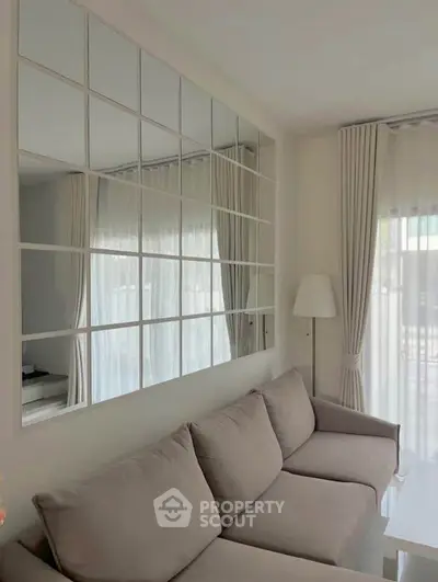 Elegant living room with modern decor and large mirrored wall enhancing natural light.