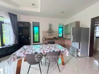 Modern kitchen with dining area, featuring stainless steel appliances and large windows for natural light.