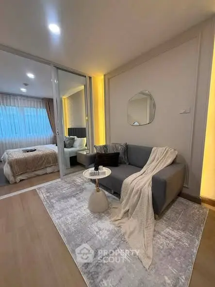Modern living room with cozy sofa and stylish decor adjacent to a bedroom with soft lighting.