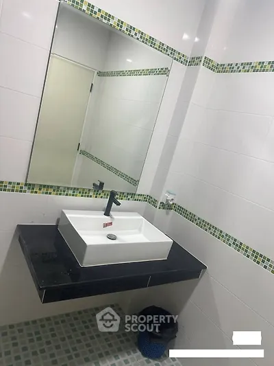Modern bathroom with stylish sink and mirror, featuring elegant tile design.