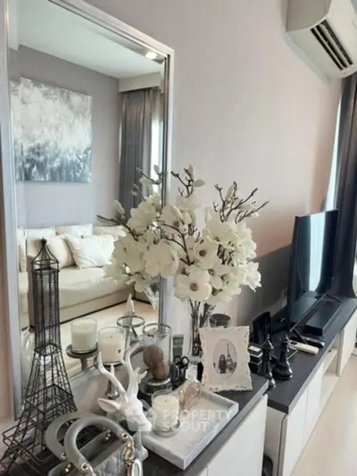 Elegantly styled living room with chic decor and modern amenities, featuring a plush white sofa, sleek entertainment unit, and tasteful art.