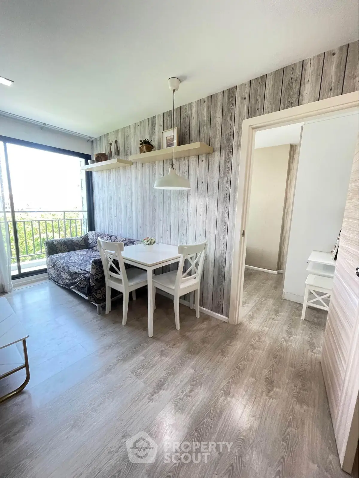 Charming living room with rustic wood paneling and cozy dining area, featuring a bright balcony view.