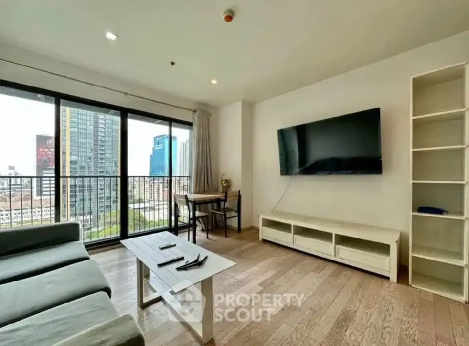 Spacious modern living room with large windows and city view, featuring a sleek TV setup and cozy seating area.