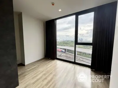 Spacious empty living room with large windows offering an expansive city view, dark curtains, and wood laminate flooring, ready for customization.