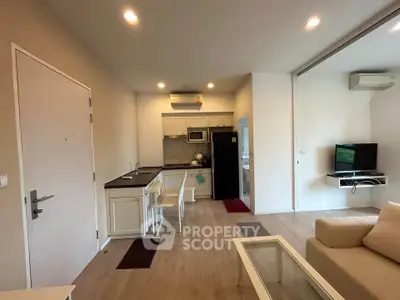 Modern open-layout living room with kitchen, featuring sleek furniture and ambient lighting.