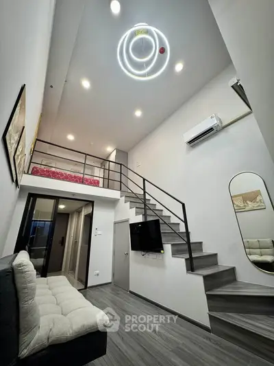 Modern loft apartment with stylish staircase and cozy living area, featuring high ceilings and contemporary lighting.