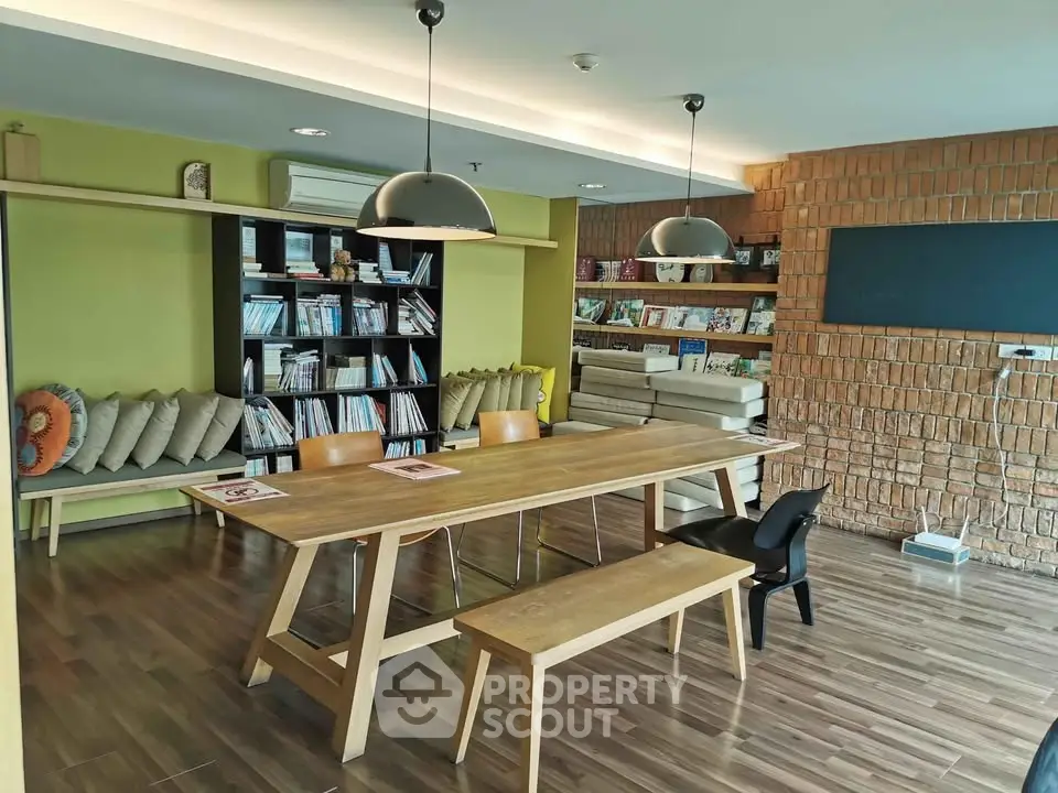 Modern co-working space with wooden table, bookshelves, and stylish lighting.