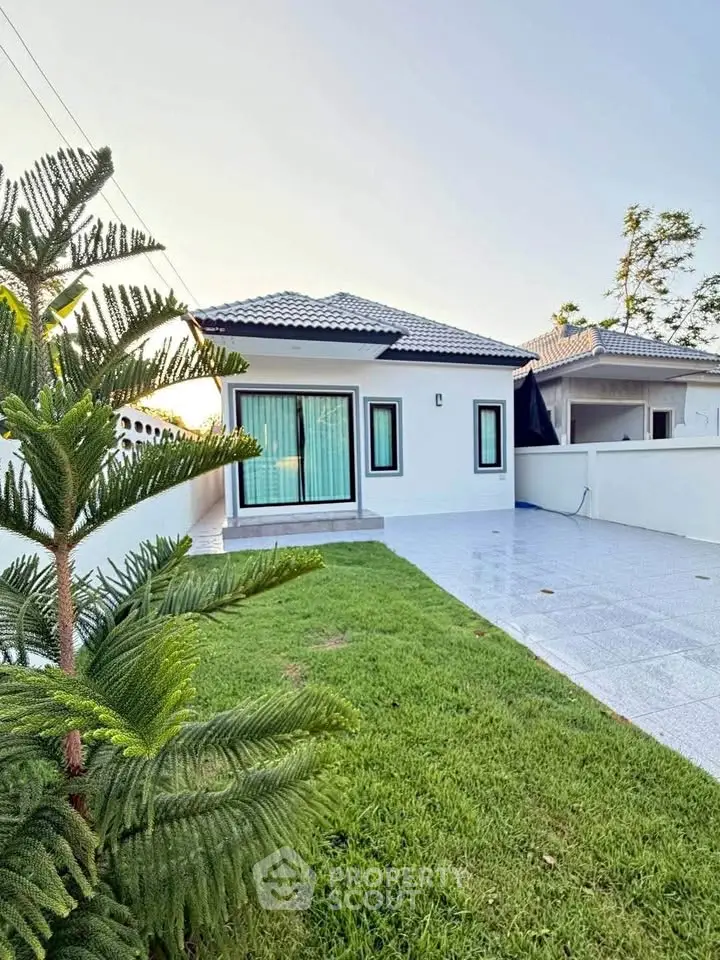 Charming single-story house with modern design, lush green lawn, and spacious driveway.