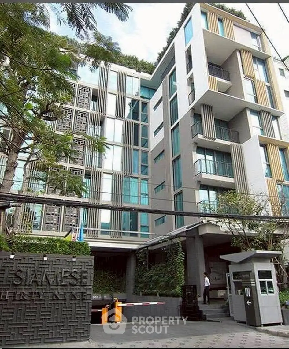 Modern apartment building with unique architectural design and lush greenery in urban setting.