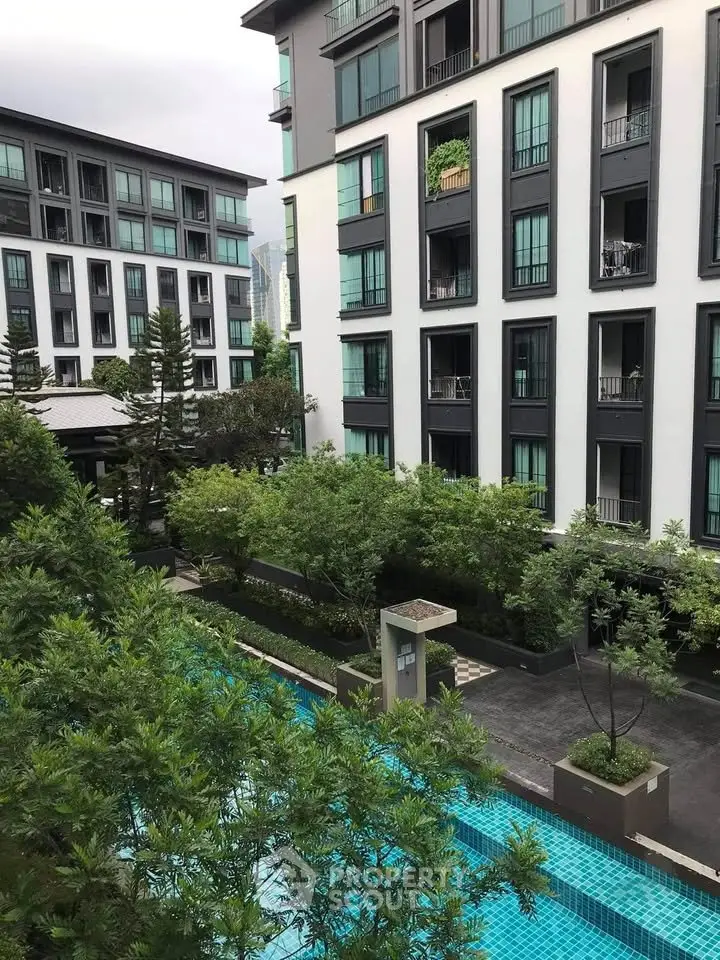 Modern apartment complex with lush greenery and inviting swimming pool view.