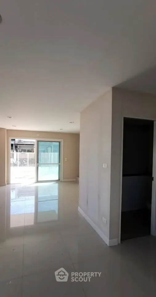 Spacious modern living area with large windows and glossy tile flooring, perfect for natural light and open living.