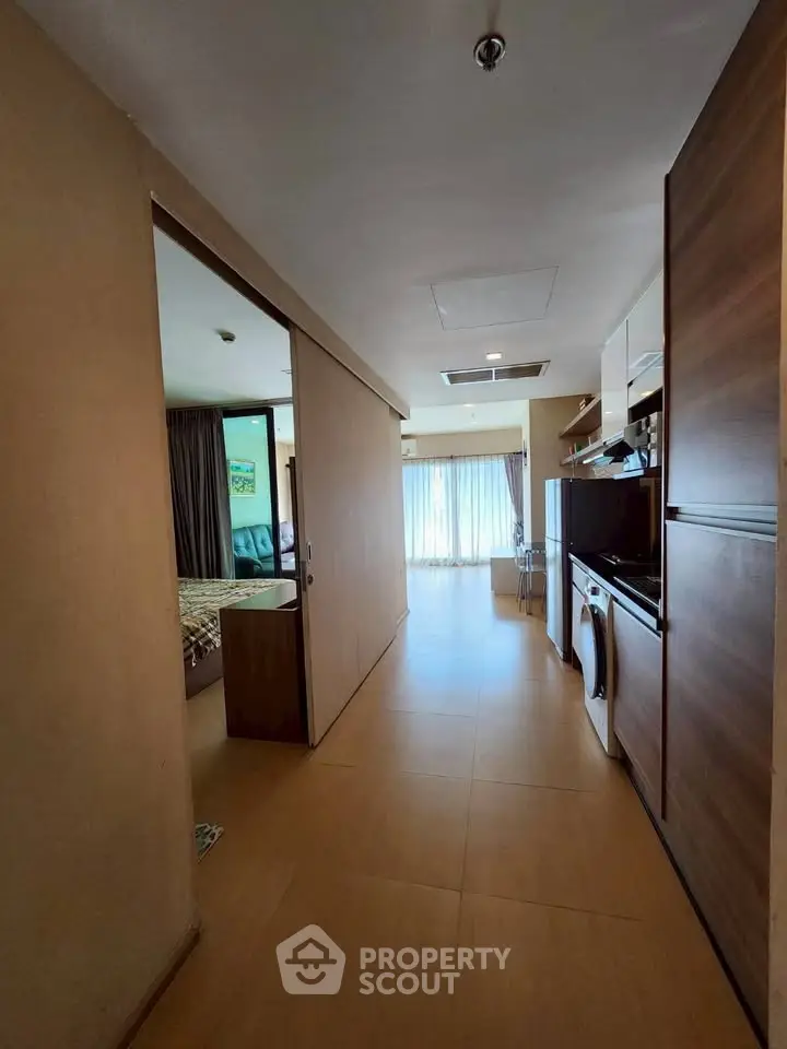 Modern apartment interior with open layout, featuring a cozy living area and compact kitchen with appliances.