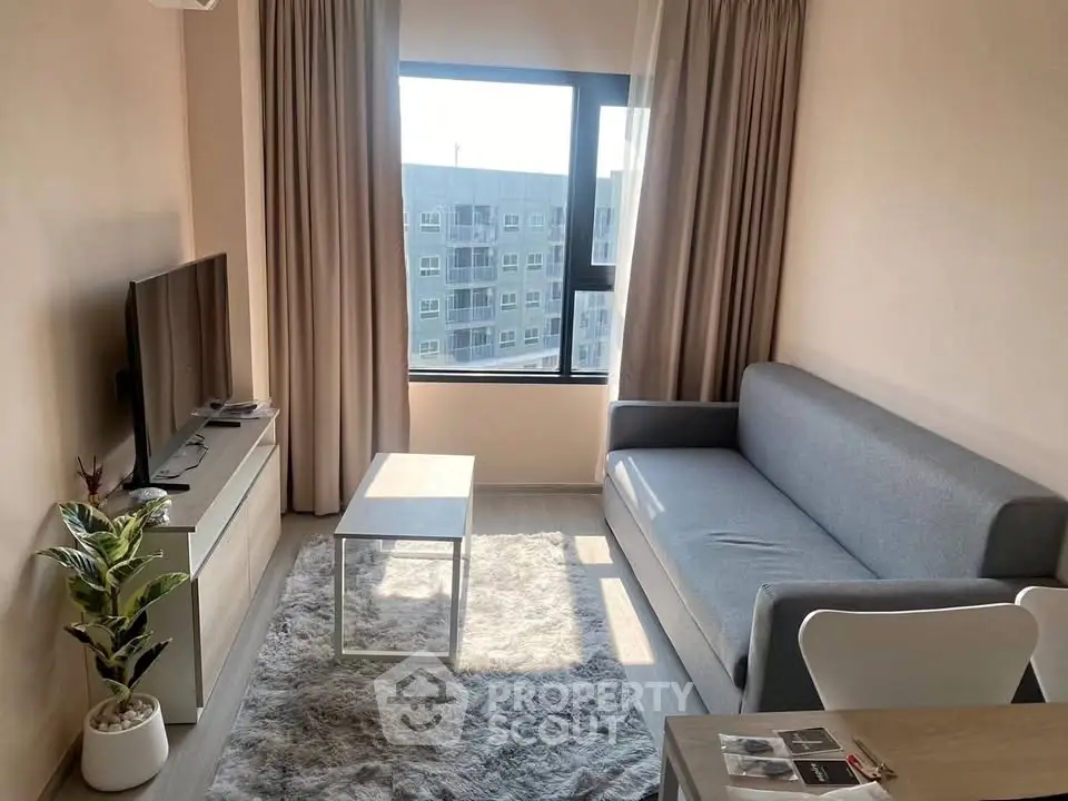 Modern living room with sleek furniture and large window offering natural light.