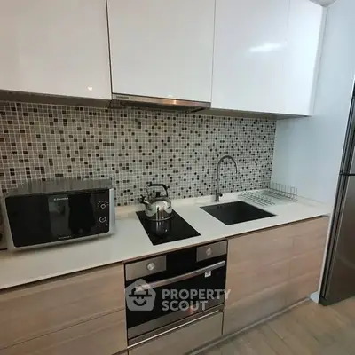 Modern kitchen with sleek cabinetry, built-in oven, and stylish backsplash.
