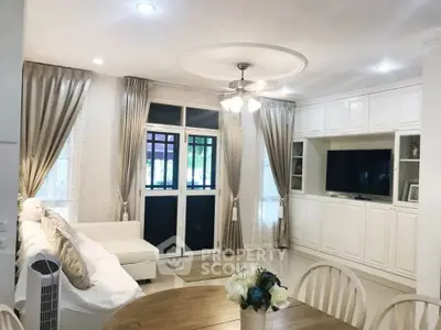 Elegant living room with white decor, large windows, and cozy seating area.