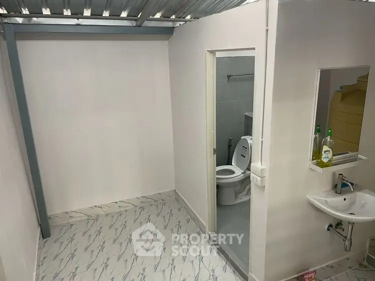 Modern bathroom with sleek design and compact layout, featuring a toilet and sink.