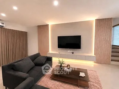Modern living room with sleek design, featuring a wall-mounted TV, cozy sofa, and elegant lighting.
