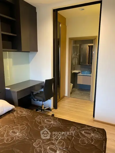 Modern bedroom with study area and ensuite bathroom in stylish apartment.