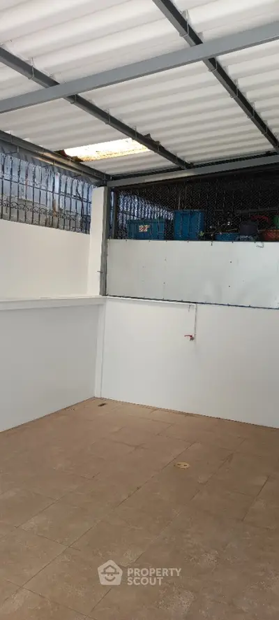 Spacious covered outdoor area with tiled flooring and metal roofing