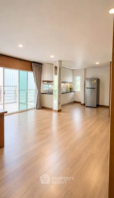 Spacious open-plan living room with modern kitchen and large balcony access.