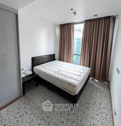 Modern bedroom with large window and city view, featuring a comfortable bed and stylish decor.