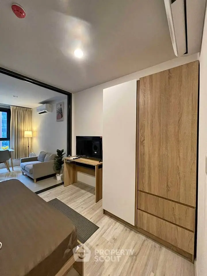 Modern studio apartment with stylish decor and open layout, featuring a cozy living area and sleek wooden furniture.