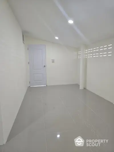 Spacious minimalist room with glossy tiled floor and white walls, perfect for versatile use in any home.