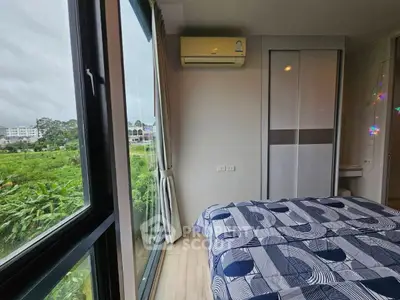 Modern bedroom with large window offering lush green views and stylish bedding.