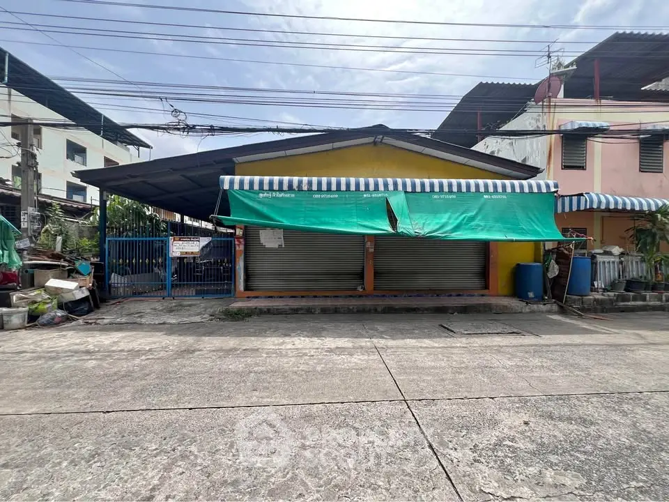 Charming single-story commercial property with a striped awning and secure metal shutters.