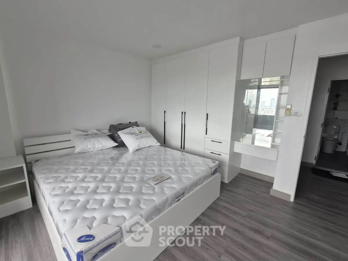 Spacious modern bedroom with white furniture and large bed in a stylish apartment.