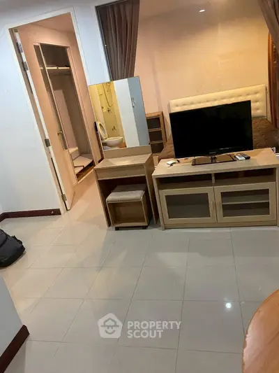 Cozy bedroom with TV and modern furnishings, featuring a walk-in closet and sleek tile flooring.