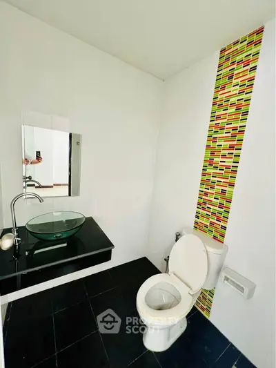 Modern bathroom with unique tile accent and sleek glass sink