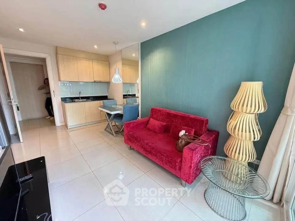 Modern living room with vibrant red sofa and stylish kitchen in open layout apartment.