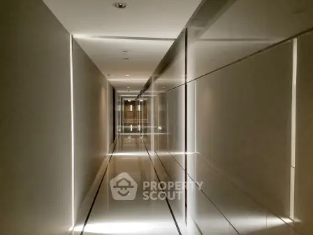 Sleek modern corridor with reflective surfaces and ambient lighting in luxury building.