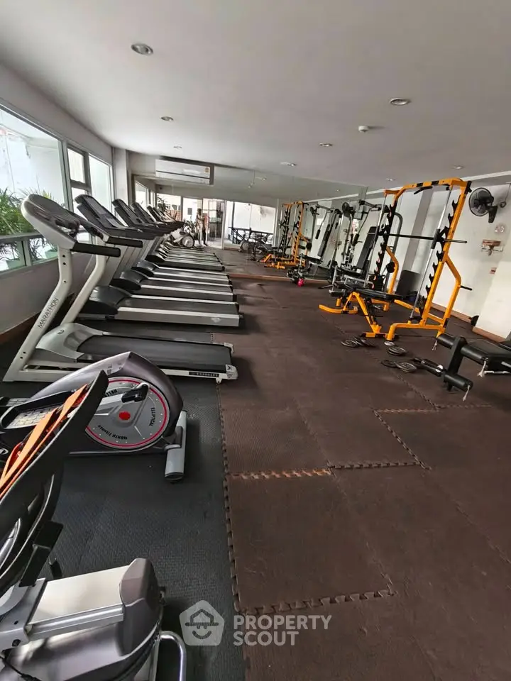 Spacious gym with modern equipment and large mirrors in a residential building.