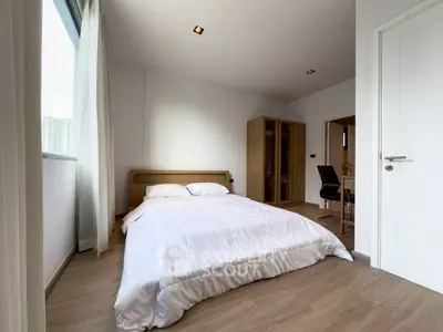 Spacious bedroom with modern decor and natural light in a stylish apartment.