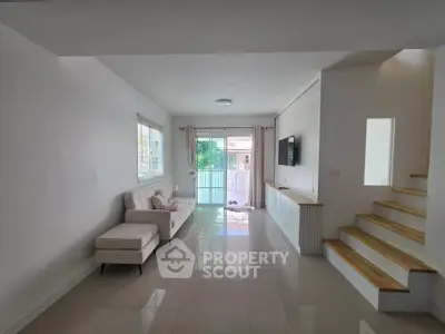 Spacious modern living room with sleek design and natural light, featuring a cozy sofa and stylish staircase.