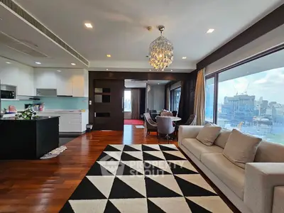 Luxurious open-plan living room with city view, modern kitchen, and elegant chandelier.