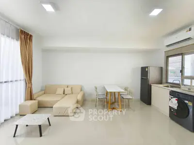 Modern living room with beige sofa, dining table, and kitchen appliances in open layout