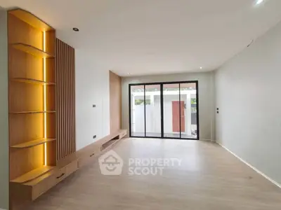 Spacious modern living room with built-in wooden shelves and large windows.