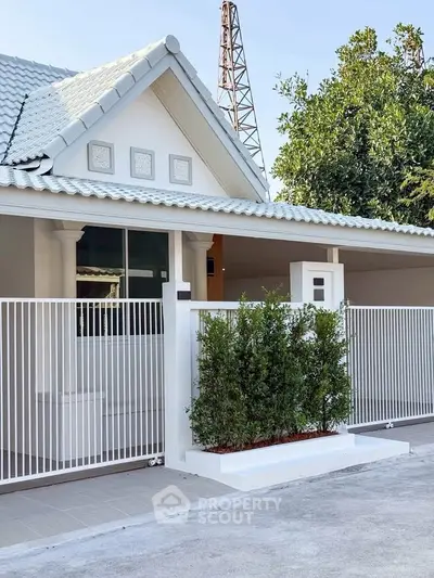 Charming single-story home with white picket fence and lush greenery, perfect for serene living.