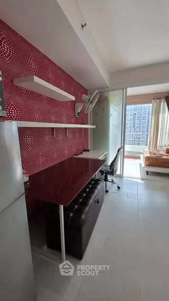 Modern studio apartment with stylish red accent wall and balcony view.