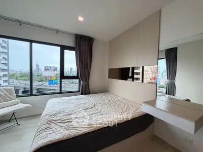 Modern bedroom with large windows offering city views, featuring sleek design and cozy ambiance.