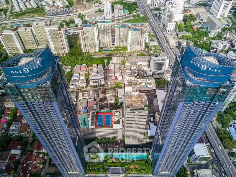 Stunning aerial view of luxury high-rise towers with cityscape backdrop, showcasing modern urban living.