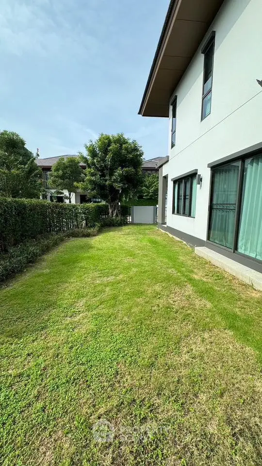 Charming residential garden with lush green lawn and modern house exterior.