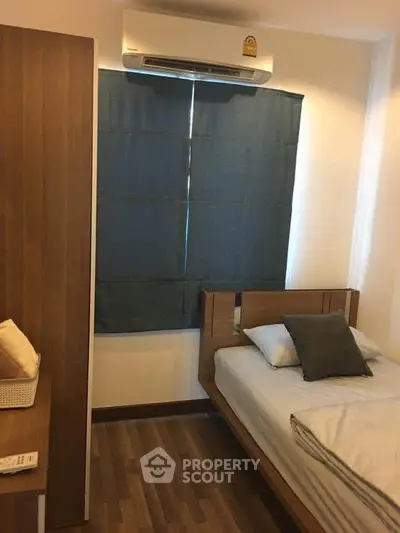 Cozy bedroom with wooden flooring and air conditioning, perfect for relaxation.